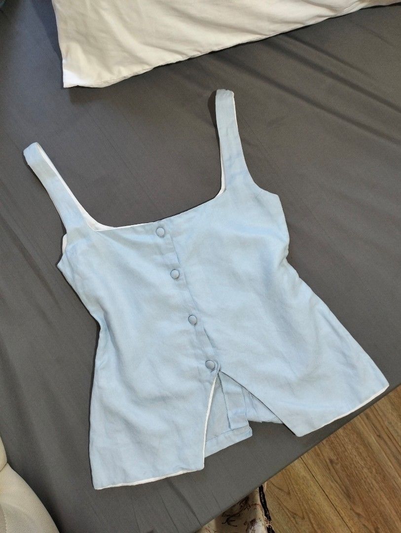 Cariño light blue button-front tank top size XS (Category: Sleeveless) located in Manila. Submitted by jasja (Listing ID 1468085267, Image 2). Description: - Brand: Cariño - No WW - Size: XS - Color: Light blue - Design: Sleeveless with square neckline and matching front buttons - Lining: White interior lining - Condition: Good overall, with some yellowing visible on the inside collar and strap lining - Origin: Made in the Philippines.