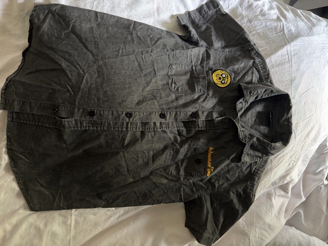Cartoon Network Adventure Time Jake button-down shirt (Category: Tshirts & Polo Shirts ) located in General Santos City (Dadiangas). Submitted by jwtfg (Listing ID 1468112074, Image 2). Description: - Official Cartoon Network Adventure Time merchandise - Color: Dark grey short-sleeve button-down shirt - Back details: Embroidered Adventure Time text and Jake graphic - Front details: Dual chest pockets with embroidered logo and yellow Jake patch .