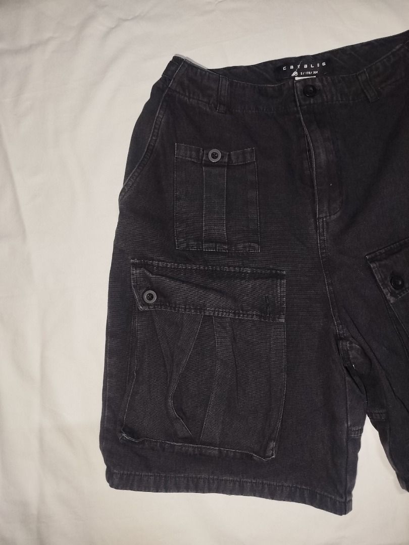 Catalog Black Cargo Shorts (Category: Shorts) located in Cavite. Submitted by raxcollection (Listing ID 1468067020, Image 3). Description: - Brand: Catalog - Color: Dark greyish black - Size: S (Tag: 170/76A) - Material: Sturdy, durable fabric construction - Features: Multiple front leg pockets with secure button closures, convenient belt loops, and classic button fly - Condition: well-maintained Flat Lay Measurements: Waist: 15 inch Length: 22 i