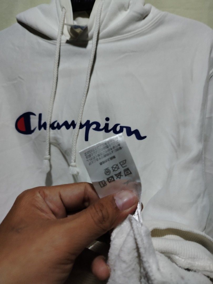 Champion White Hoodie Sweatshirt Medium (Category: Hoodies) located in Caloocan City. Submitted by vincefresn21903 (Listing ID 1468281752, Image 3). Description: - Brand: Champion - Style: Pullover hoodie with standard fit - Color: Classic White - Size: Medium - Design: Large script logo across the chest - Features: Kangaroo front pocket, drawstring hood, ribbed cuffs and hem - Detail: Small embroidered 'C' patch on the left wrist - Material: Com