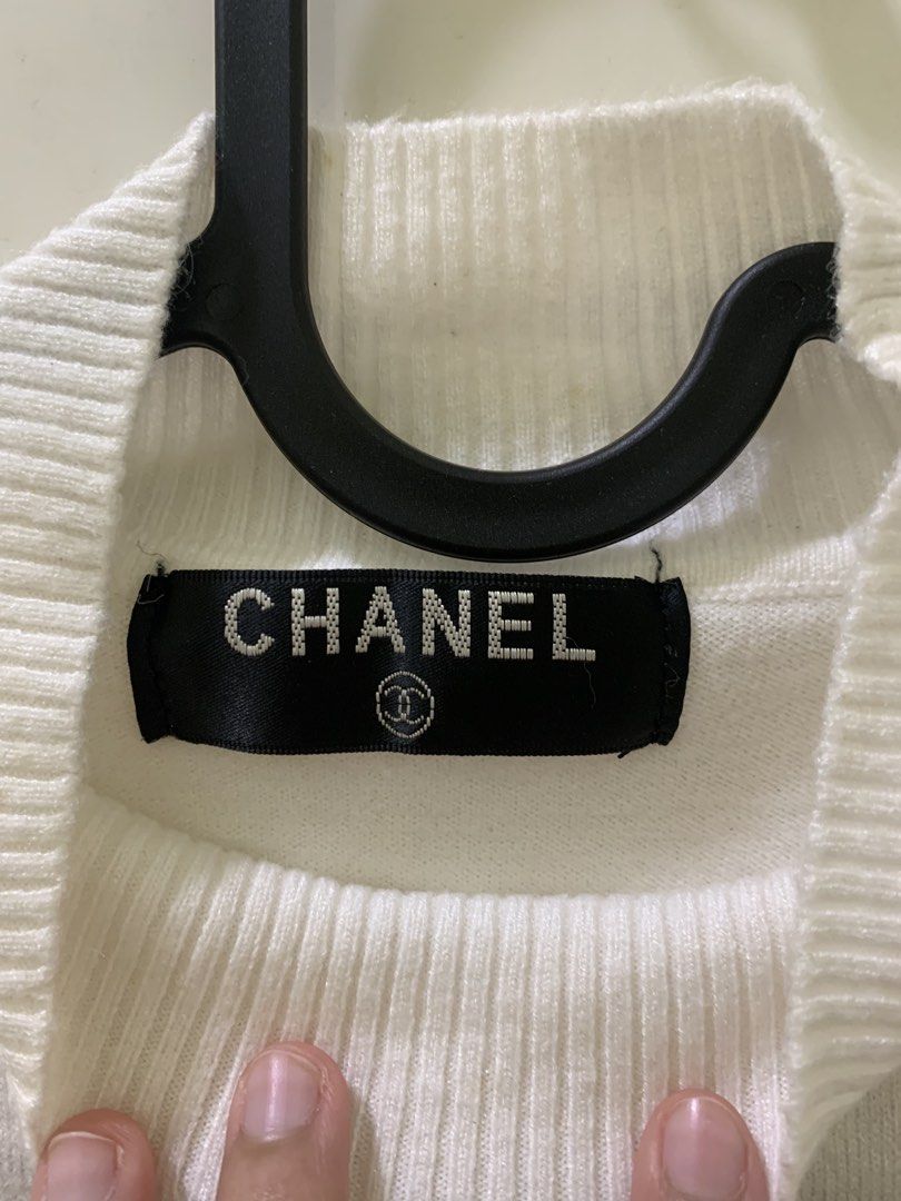 Chanel White Short Sleeve Rhinestone Eiffel Tower Sweater (Category: Shirts) located in Manila. Submitted by jo.arban (Listing ID 1468224194, Image 3). Description: - Color: White - Style: Short sleeve knit sweater with mock neck - Design: Detailed rhinestone graphic featuring the Eiffel Tower, floral motifs, and Chanel lettering - Finishes: Ribbed collar, cuffs, and hem for a snug fit - Branding: Authentic black Chanel label inside the neckline 