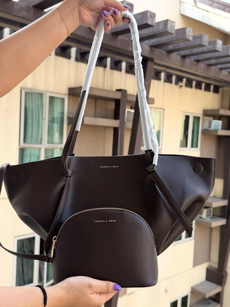 Charles & Keith Dark Brown Tote Bag with Pouch (Category: Tote Bags) located in Manila. Submitted by fritzieeeeeganda (Listing ID 1468102544, Image 2). Description: - Brand: Charles & Keith - Color: Dark brown - Inclusions: Matching half-moon pouch - Design: Structured slouchy style with thin shoulder straps - Perfect for: Daily commute, school essentials, or everyday use.