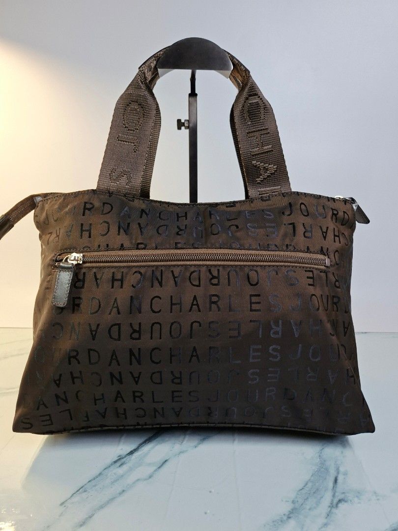 Charles Jourdan Brown Monogram Tote Handbag (Category: Tote Bags) located in Pasay City. Submitted by onick_79 (Listing ID 1468239079, Image 2). Description: - Brand: Charles Jourdan - Color: Dark Brown with all-over monogram letter print - Material: Durable nylon with matching hardware - Closure: Secure top zipper closure - Pockets: Roomy main compartment with a structured rectangular base and 1 exterior vertical zip pocket on the back - Straps: