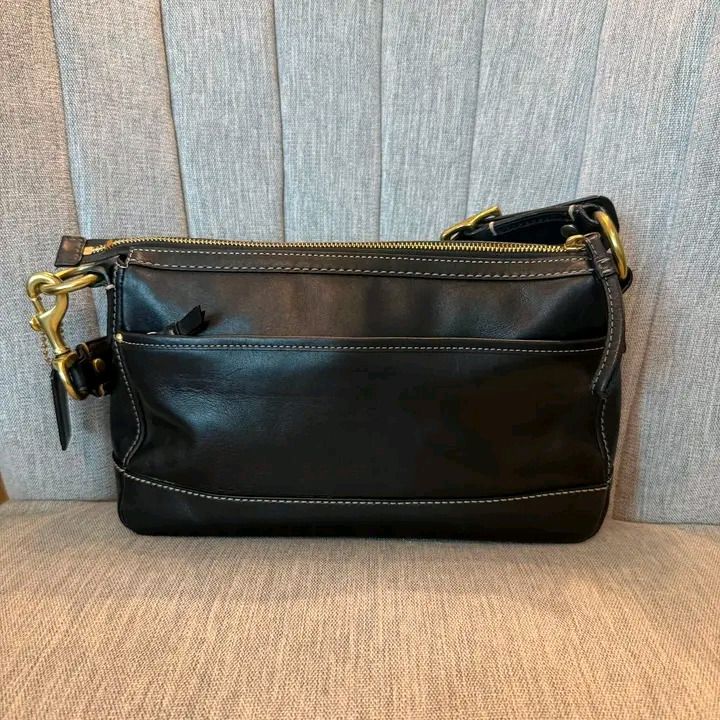 Coach Black Leather Shoulder Bag with Front Pockets (Category: Luxury Bags & Wallets) located in Pagadian. Submitted by mamithere (Listing ID 1468116066, Image 2). Description: - Brand: Coach - Material: Genuine black leather with contrast white stitching - Hardware: Brass - Pockets: Two front utility pockets with turnlock closures, zippered main compartment, and exterior back slip pocket - Includes: Signature leather Coach hangtag and detachable