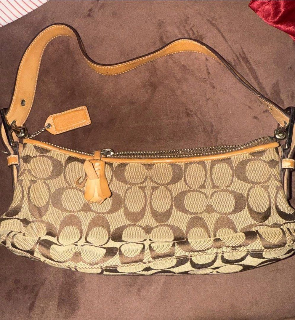 Coach eastwest baguette (Category: Luxury Bags & Wallets) located in Manila. Submitted by esethy (Listing ID 1468060924, Image 2). Description: - Authentic Coach signature C jacquard fabric with tan leather trim - Classic shoulder bag silhouette with secure top zip closure - Single adjustable leather strap with matching hangtag - Clean interior with creed patch and serial number B055-6371 - Dark brown fabric lining - Minor signs of everyday wear 