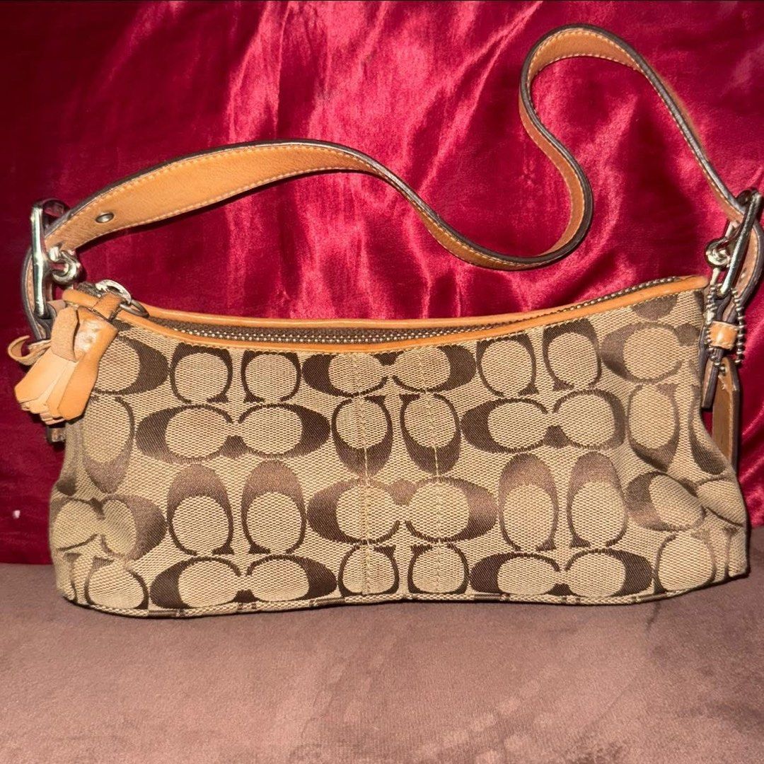Coach eastwest baguette (Category: Luxury Bags & Wallets) located in Manila. Submitted by esethy (Listing ID 1468060924, Image 1). Description: - Authentic Coach signature C jacquard fabric with tan leather trim - Classic shoulder bag silhouette with secure top zip closure - Single adjustable leather strap with matching hangtag - Clean interior with creed patch and serial number B055-6371 - Dark brown fabric lining - Minor signs of everyday wear 