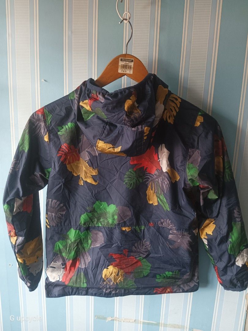 COLUMBIA REVERSIBLE JACKET (Category: Hiking & Camping) located in Cebu City. Submitted by glennbryceland031185 (Listing ID 1468082802, Image 3). Description: Columbia youth or kids windbreaker jacket featuring a colorful tropical plant and leaf pattern. Brand: Columbia Sportswear Design: Navy blue base with a vibrant botanical/tropical leaf print (featuring red, yellow, and white foliage) Features: Attached hood, full-length front zipper, and el