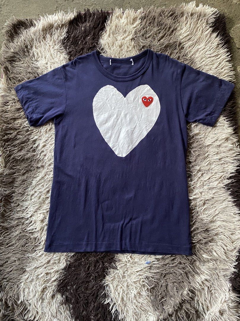 COMME des GARÇONS Play Navy Heart Tee Shirt (Category: Shirts) located in Manila. Submitted by coollion.19b40f (Listing ID 1468256021, Image 1). Description: Dark blue t-shirt with large white heart graphic on the front. Embroidered red heart logo patch with eyes on top of the white heart. Short sleeves, crew neck. Clean solid back. Simple everyday tee..