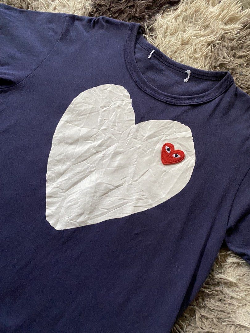 COMME des GARÇONS PLAY Navy Tee with Heart Logo (Category: Shirts) located in Caloocan City. Submitted by remythrift (Listing ID 1468087381, Image 2). Description: - Brand: Comme des Garçons PLAY - Color: Navy Blue - Design: Large white heart print with signature red embroidered heart eye patch - Details: Classic crew neck, short sleeves, clean hem stitching - Condition: Great casual wear piece with very slight wrinkles on the white graphic - Sty