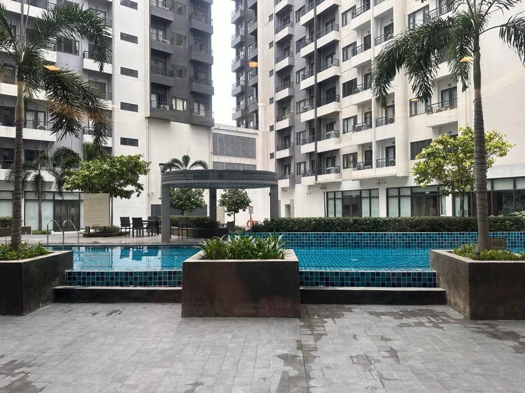 Condo Unit with City View and Pool Access (Category: Apartments & Condos) located in Manila. Submitted by ryanvflo36419 (Listing ID 1468070793, Image 1). Description: - Move-in ready condominium unit - Dark-framed windows with urban and parking area views - Access to shared outdoor swimming pool and palm tree surroundings inclusive of assoc.