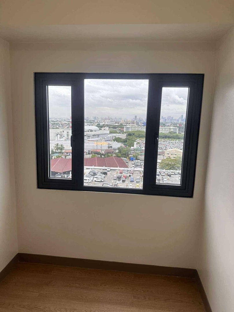 Condo Unit with City View and Pool Access (Category: Apartments & Condos) located in Manila. Submitted by ryanvflo36419 (Listing ID 1468070793, Image 3). Description: - Move-in ready condominium unit - Dark-framed windows with urban and parking area views - Access to shared outdoor swimming pool and palm tree surroundings inclusive of assoc.