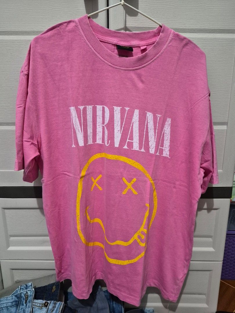 Cotton On Nirvana Graphic Tee Pink Size S (Category: Shirts) located in Antipolo. Submitted by prinsesa_dianne (Listing ID 1468247264, Image 1). Description: - Brand: Cotton On (Official 2020 Nirvana Merch) - Size: S - Color: Bright pink with a washed finish - Design: Famous Nirvana smiley face print on front with bold text - Fit: Trendy boxy fit with ribbed crew neckline and short sleeves.