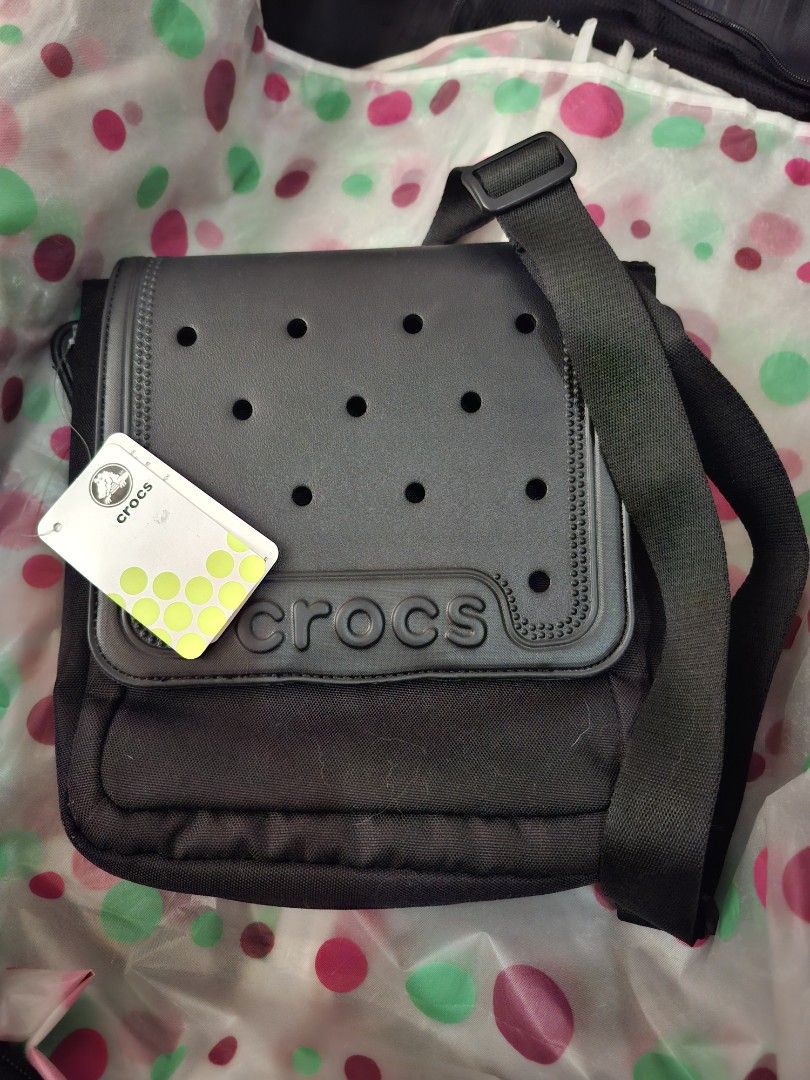 Crocs Black Messenger Crossbody Bag (Category: Cross-body Bags) located in Pasig City. Submitted by bolddeer_2ab1c6 (Listing ID 1468223444, Image 2). Description: - Brand: Crocs - Color: Black - Condition: Brand new with original tags attached (unused) - Material: Fabric main body with rubber-look front panel - Features: Adjustable strap for a custom fit, iconic front ventilation hole design, and embossed Crocs logo text - Perfect for daily use, 