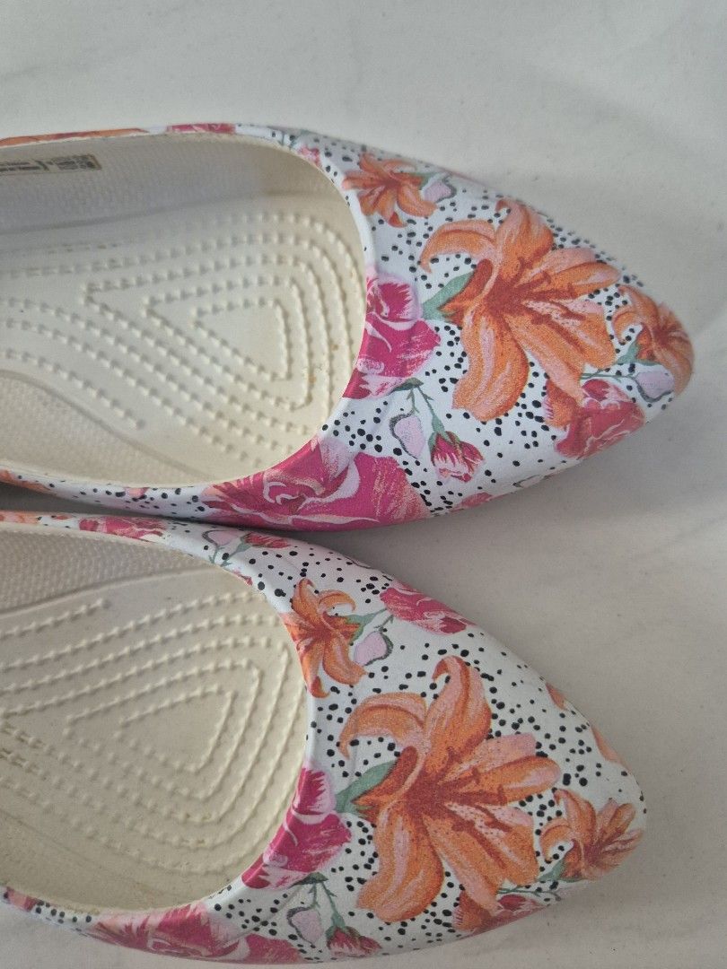 Crocs Floral Pointed Toe Flats W5 (Category: Flats & Sandals) located in San Jose. Submitted by nova2023 (Listing ID 1468074957, Image 2). Description: - Brand: Crocs - Style: Slip-on flats with a sleek pointed toe - Design: Vibrant orange lily and pink rose print on a polka dot background - Comfort: Iconic Crocs comfort footbed for all-day cushioning - Size: Women's US 5 - Condition: Good, with minor wear on the soles from previous use.