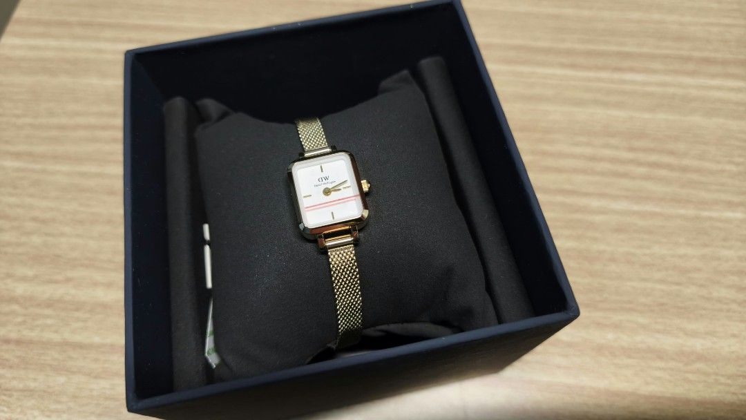 Daniel Wellington Quadro Mini Watch DW00100725 (Category: Women's Watches) located in San Mateo. Submitted by lula.lei (Listing ID 1468085821, Image 1). Description: - Brand: Daniel Wellington Quadro Mini - Color/Finish: Elegant gold tone - Dial: Rectangular white with a delicate horizontal pink stripe - Strap: Mesh metal - Movement: Japanese quartz - Condition: Brand new, unworn, and still wrapped on the display cushion - Inclusions: Original da