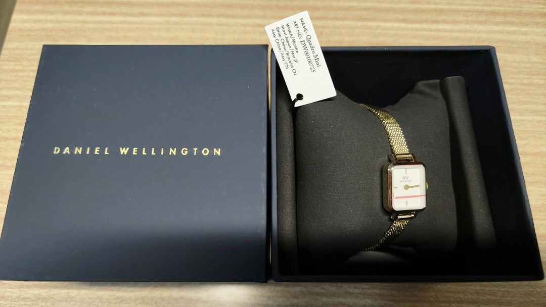 Daniel Wellington Quadro Mini Watch DW00100725 (Category: Women's Watches) located in San Mateo. Submitted by lula.lei (Listing ID 1468085821, Image 3). Description: - Brand: Daniel Wellington Quadro Mini - Color/Finish: Elegant gold tone - Dial: Rectangular white with a delicate horizontal pink stripe - Strap: Mesh metal - Movement: Japanese quartz - Condition: Brand new, unworn, and still wrapped on the display cushion - Inclusions: Original da