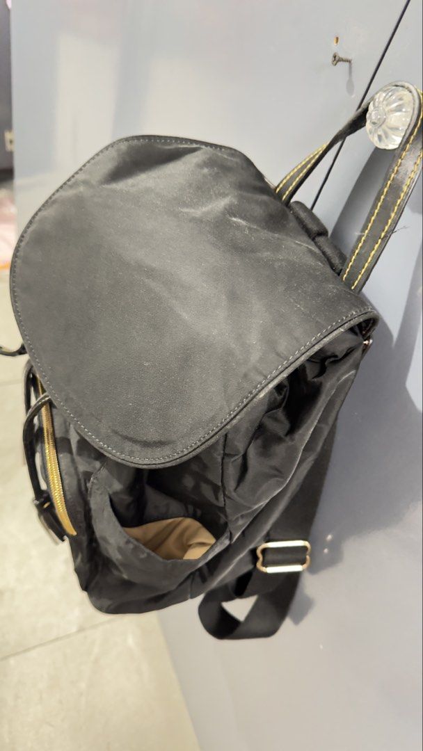 Dooney & Bourke Black Nylon Backpack (Category: Backpacks) located in Quezon City. Submitted by dendionlineshop (Listing ID 1468146862, Image 3). Description: - Brand: Dooney & Bourke - Material: Durable black nylon with contrast yellow stitching - Closure: Front flap with magnetic snap and drawstring pull - Pockets: Front zipper pocket, side slip pockets, and interior zippered pocket - Straps: Top carry handle and adjustable shoulder straps - Ha