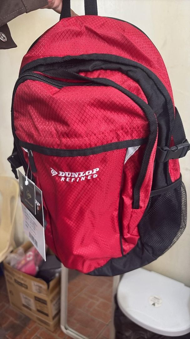 Dunlop Refined Red Backpack Daypack (Category: Backpacks) located in Davao. Submitted by luckyturtle.aa6ccf (Listing ID 1468175420, Image 2). Description: - Brand: Dunlop Refined - Color: Bright red with black accents - Material: Durable and lightweight polyester - Dimensions: Approx. 24 x 42 x 14 cm - Features: Front zip compartment and dual black mesh side pockets - Condition: Brand new with original product tag and barcode attached - Best for: