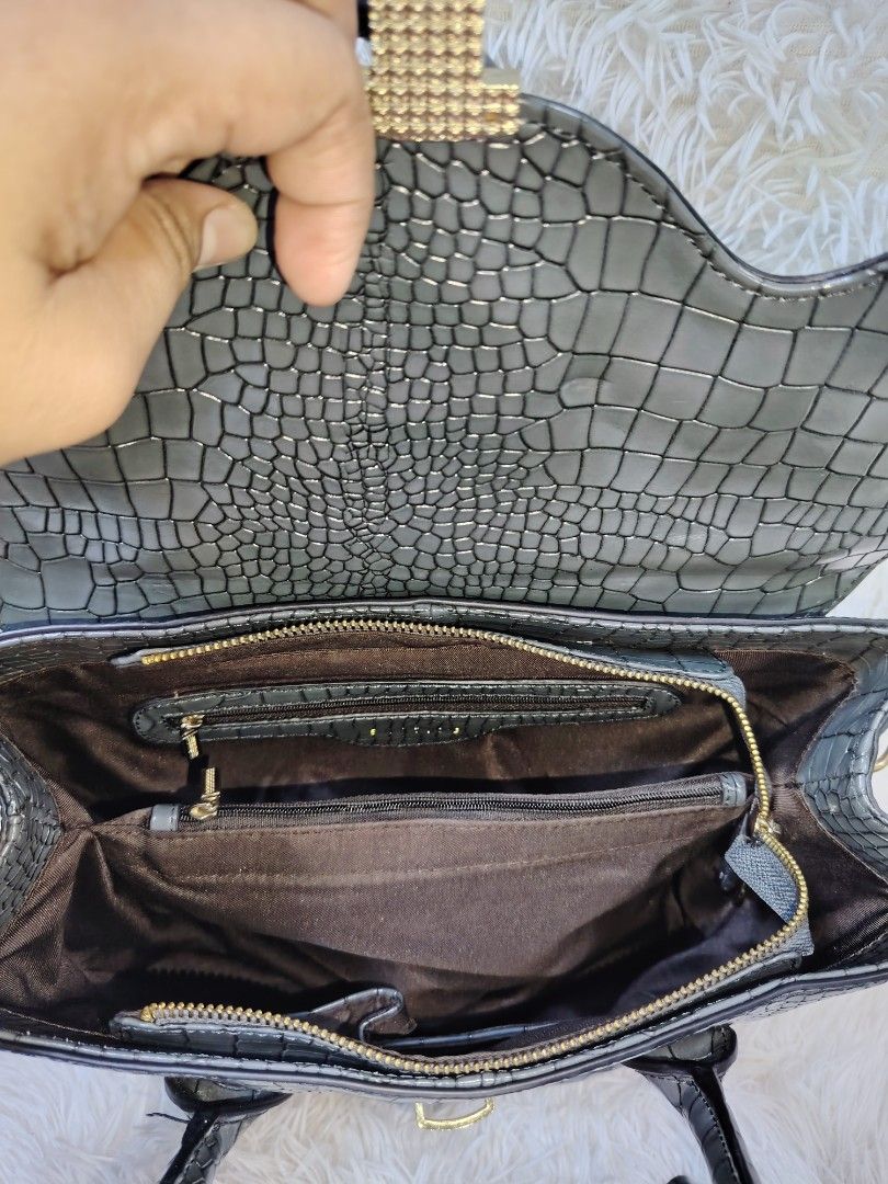 Eastside Grey Crocodile Texture Handbag with Strap (Category: Cross-body Bags) located in Quezon City. Submitted by zhelcloset01 (Listing ID 1468236479, Image 3). Description: - Color: Grey with stylish crocodile texture pattern throughout - Design: Structured shape with elegant gold-tone hardware and flap closure with metallic accent - Versatility: Includes dual top handles and a detachable strap for shoulder or hand carry - Interior: Dark brown
