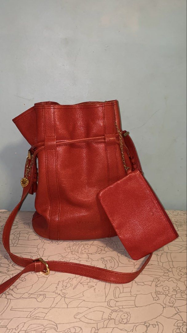 Emanuel Ungaro Red Leather Bucket Bag with Pouch (Category: Luxury Bags & Wallets) located in Manila. Submitted by ryoughhthrift (Listing ID 1468094732, Image 1). Description: - Brand: Emanuel Ungaro - Material: Premium textured leather in a bright red shade - Closure: Secure drawstring top - Strap: Adjustable shoulder strap for a custom fit - Bonus: Includes a matching detachable zippered pouch connected by a chic gold chain - Base: Flat oval ba