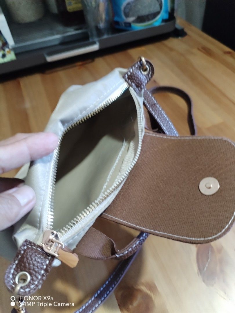 Everyday bag (Category: Purses & Pouches) located in Muntinlupa City. Submitted by arciagamaryann68 (Listing ID 1468104855, Image 3). Description: - Style: Everyday casual crossbody / shoulder bag - Color: Beige body with brown textured flap and strap details - Material: Durable nylon with leatherette accents - Closure: Zipper main compartment with snap-button flap - Strap: Adjustable and removable long strap - Condition: Excellent, well-maintain