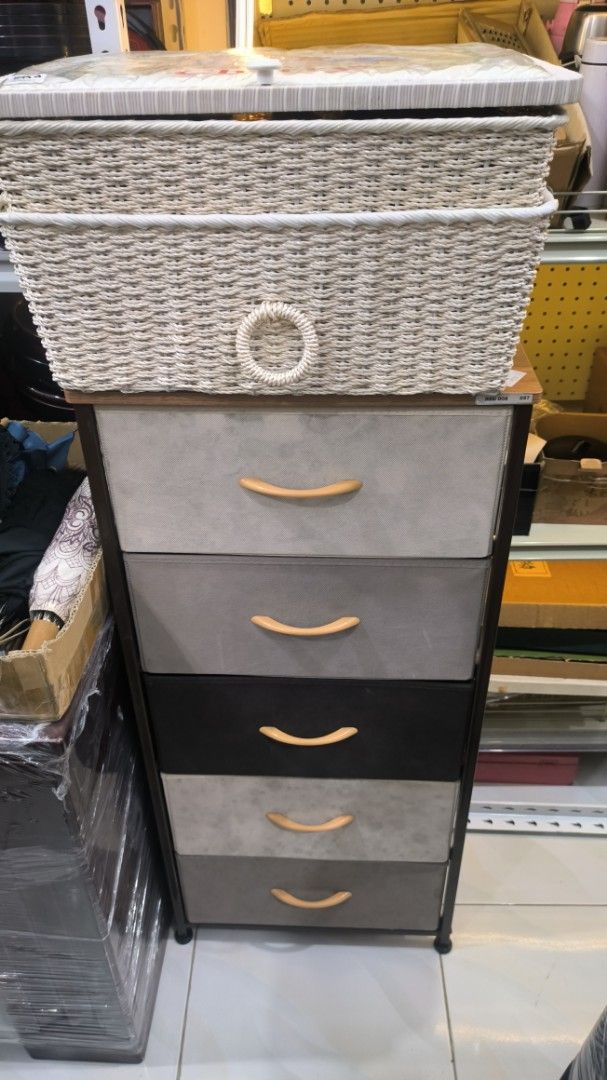 Fabric Storage Tower with Wicker Basket Top (Category: Storage Boxes & Baskets) located in Lopez. Submitted by mysticocean.1b4b80 (Listing ID 1468088973, Image 2). Description: - Type: Tall storage unit with 5 fabric drawers and top basket - Colors: Shades of grey and black - Features: Wooden drawer handles and a wicker-style basket with lid and ring pull - Ideal for: Organizing clothes, accessories, and general clutter - Placement: Perfect for b