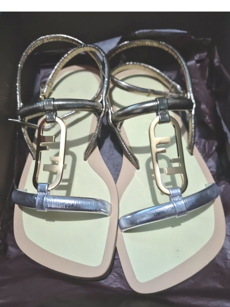 Fendi Flat Sandals Metallic Gold Silver (Category: Flats & Sandals) located in Paranaque City. Submitted by calm_youngstore7 (Listing ID 1468069401, Image 3). Description: - Brand: Fendi - Style: Flat sandals with square toe and ankle wrap buckle closure - Color/Finish: Metallic gold and silver with a pale yellow footbed - Details: Iconic FF hardware logo across the front strap - Inclusion: Complete set with original box, paper shopping bag, and 