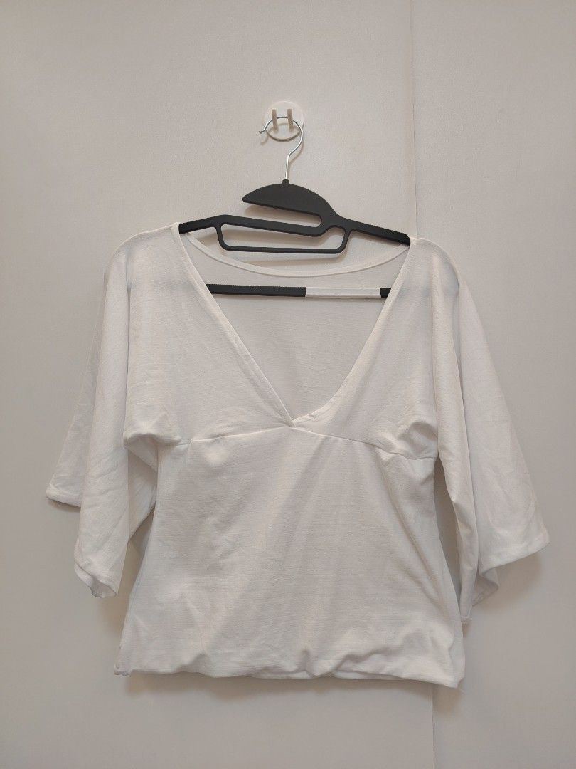 FHILAR White V-Neck Top (Category: Blouses) located in Manila. Submitted by wisepenguin.89f414 (Listing ID 1468188347, Image 2). Description: - Color & Style: White V-neck top with wide sleeves and empire waistline - Material: Soft cotton feel, clean fabric with no stains or holes - Size: XL-XXL (Pink tag: ENILAR) - Fit: Hits around the hips - Versatility: Easy to match with jeans or skirts.