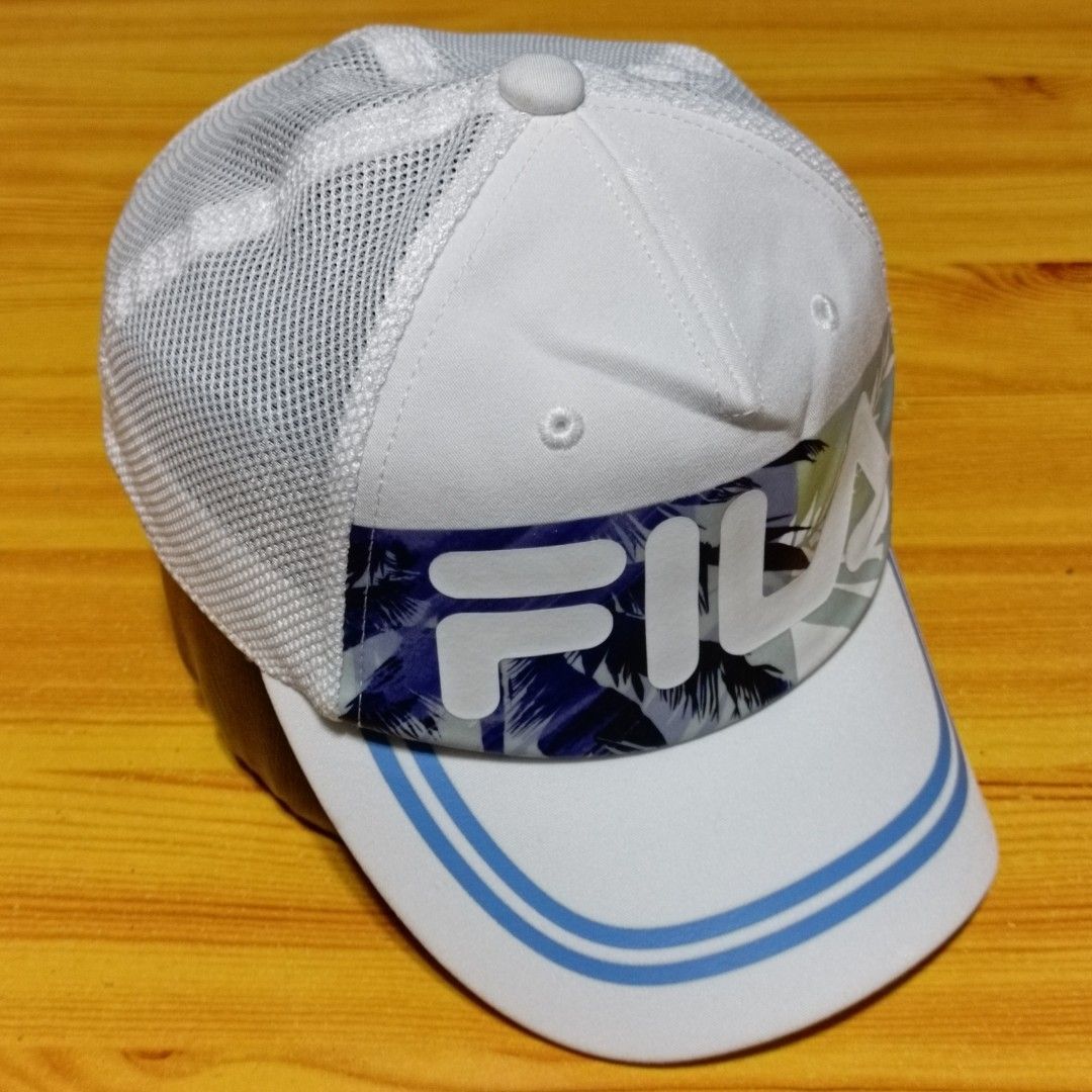 FILA White Mesh Tropical Print Snapback Cap (Category: Caps & Hats) located in Manila. Submitted by caps08 (Listing ID 1468257649, Image 1). Description: - Brand: FILA - Color: White with tropical leaf print and light blue brim stripes - Design: Mesh back panels for breathability, large FILA front logo, and small embroidered logo at the back - Fit: Adjustable plastic snapback closure (Size: 52-54cm) - Style Code: K18B022223F - Condition: Brand ne