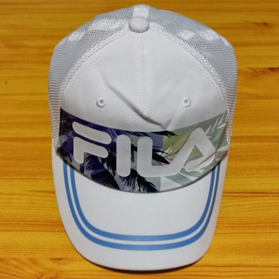 FILA White Mesh Tropical Print Snapback Cap (Category: Caps & Hats) located in Manila. Submitted by caps08 (Listing ID 1468257649, Image 2). Description: - Brand: FILA - Color: White with tropical leaf print and light blue brim stripes - Design: Mesh back panels for breathability, large FILA front logo, and small embroidered logo at the back - Fit: Adjustable plastic snapback closure (Size: 52-54cm) - Style Code: K18B022223F - Condition: Brand ne