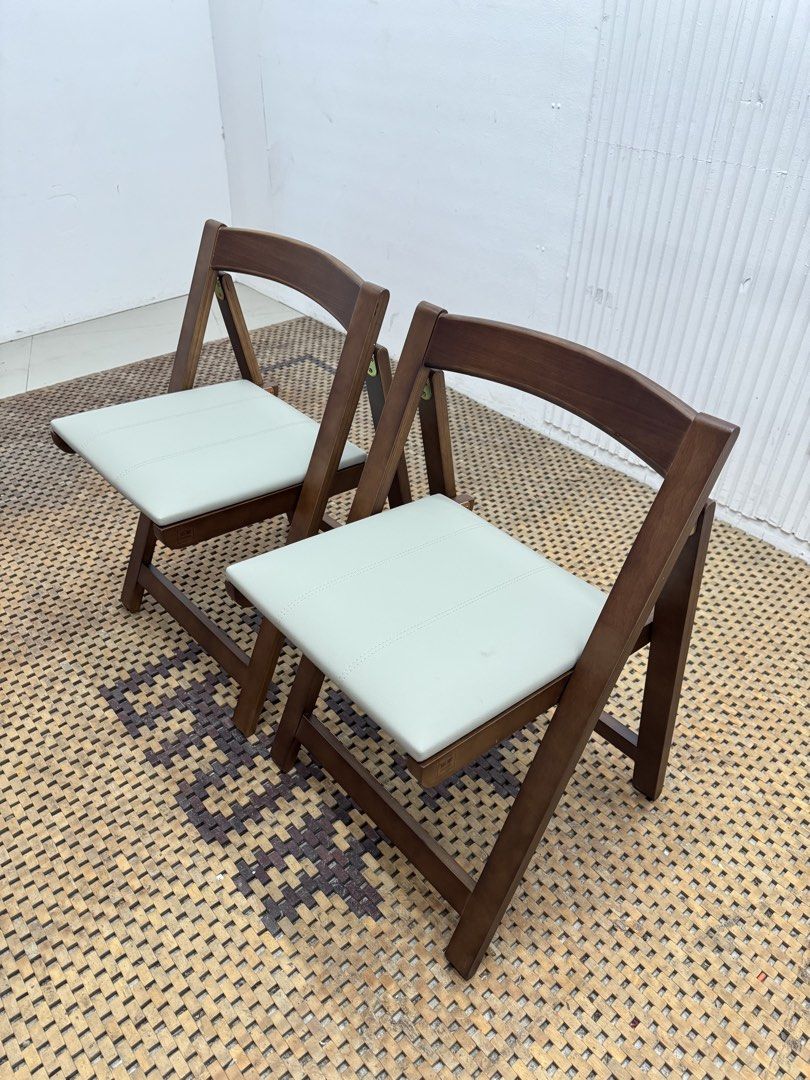 Folding chair (Category: Chairs) located in Quezon City. Submitted by matetdevis13 (Listing ID 1468231123, Image 3). Description: NEW! VIVI CASA Set of 2 Brown Wooden Folding Dining Chairs with Cream Cushioned Seats Price: 4,900 L17.5 x W18 x H27/17.5 Brand New with box Code JMD15-M117A They feature a warm brown wooden frame, cream padded seats, curved backrests, and a foldable design for easy storage..