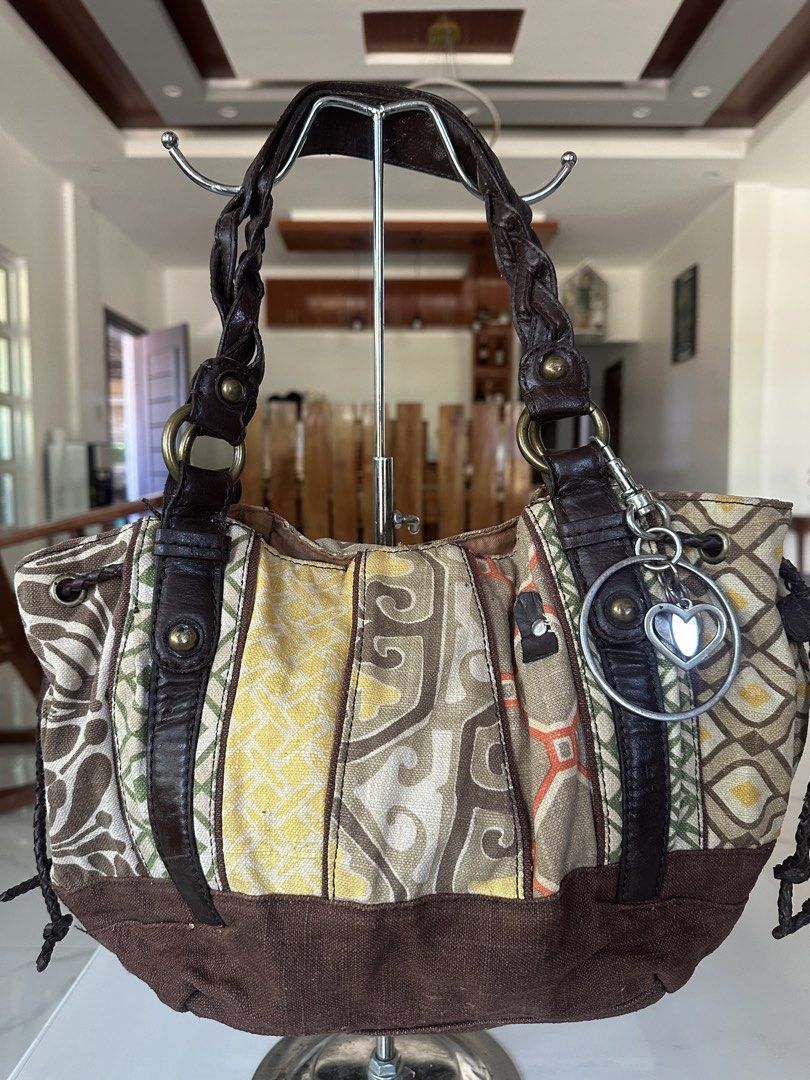 Fossil Patchwork Canvas Shoulder Bag (Category: Shoulder Bags) located in Manila. Submitted by goldenhorse-dafc (Listing ID 1468094731, Image 1). Description: - Brand: Fossil - Style: Shoulder bag - Color/Material: Brown, beige, and yellow mixed fabric panels - Straps: Braided leather straps - Hardware: Bronze hardware - Exterior: Front slip pocket with leather patch logo and adorable attached heart charm - Interior: Brown fabric lining with a zi