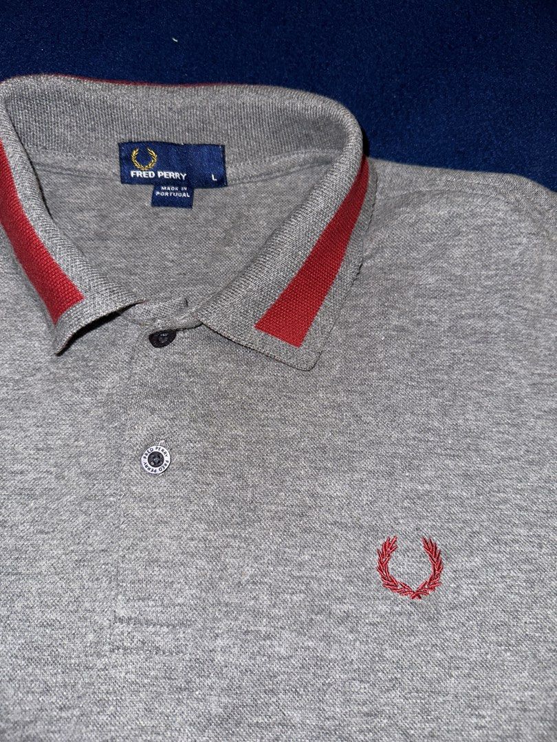 Fred Perry polo shirt L (Category: Tshirts & Polo Shirts ) located in Quezon City. Submitted by mancave_stuff (Listing ID 1468165311, Image 3). Description: • Brand: Fred Perry • Size: L (Large) W19” x L27” • Color: Heather Grey / Red • Origin: Made in Portugal • Material: Premium piqué cotton (breathable and high-quality knit) • Design Elements: Contrast red collar tipping, custom Fred Perry branded buttons, and classic Laurel Wreath embroidery.