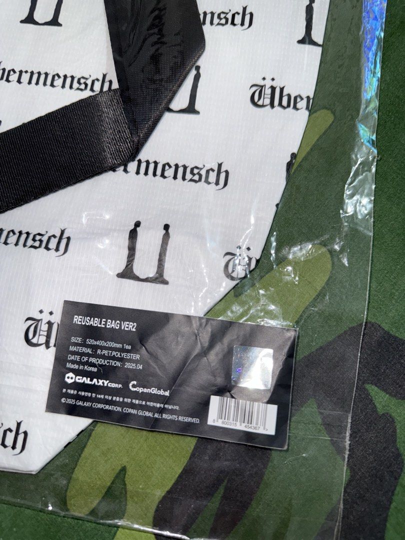 G-DRAGON UBERMENSCH Reusable Bag (Category: Music Accessories) located in Manila. Submitted by trumanblack1975 (Listing ID 1468177808, Image 3). Description: - G-DRAGON UBERMENSCH Reusable Bag (Version 2) - Color: White body with black all-over text print and black handles - Material: Sustainable r-pet polyester - Dimensions: 520 x 400 x 200 mm - Condition: Brand new, still sealed in original plastic packaging - Authenticity: Comes with official 