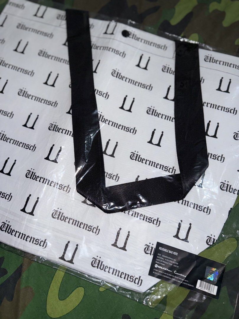 G-DRAGON UBERMENSCH Reusable Bag (Category: Music Accessories) located in Manila. Submitted by trumanblack1975 (Listing ID 1468177808, Image 2). Description: - G-DRAGON UBERMENSCH Reusable Bag (Version 2) - Color: White body with black all-over text print and black handles - Material: Sustainable r-pet polyester - Dimensions: 520 x 400 x 200 mm - Condition: Brand new, still sealed in original plastic packaging - Authenticity: Comes with official 