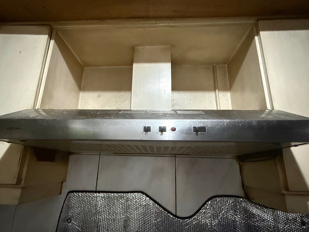 GERMANIA stainless steel kitchen range hood (Category: Hobs & Hoods) located in Mandaluyong City. Submitted by jeyviee (Listing ID 1468215206, Image 1). Description: GERMANIA stainless steel kitchen hood mounted under cabinets. Front control panel with push buttons and indicator light. Underside shows ventilation grates and filter area. Unit shows cosmetic wear, grease buildup, and surface scratches from regular kitchen use. Needs a thorough clea