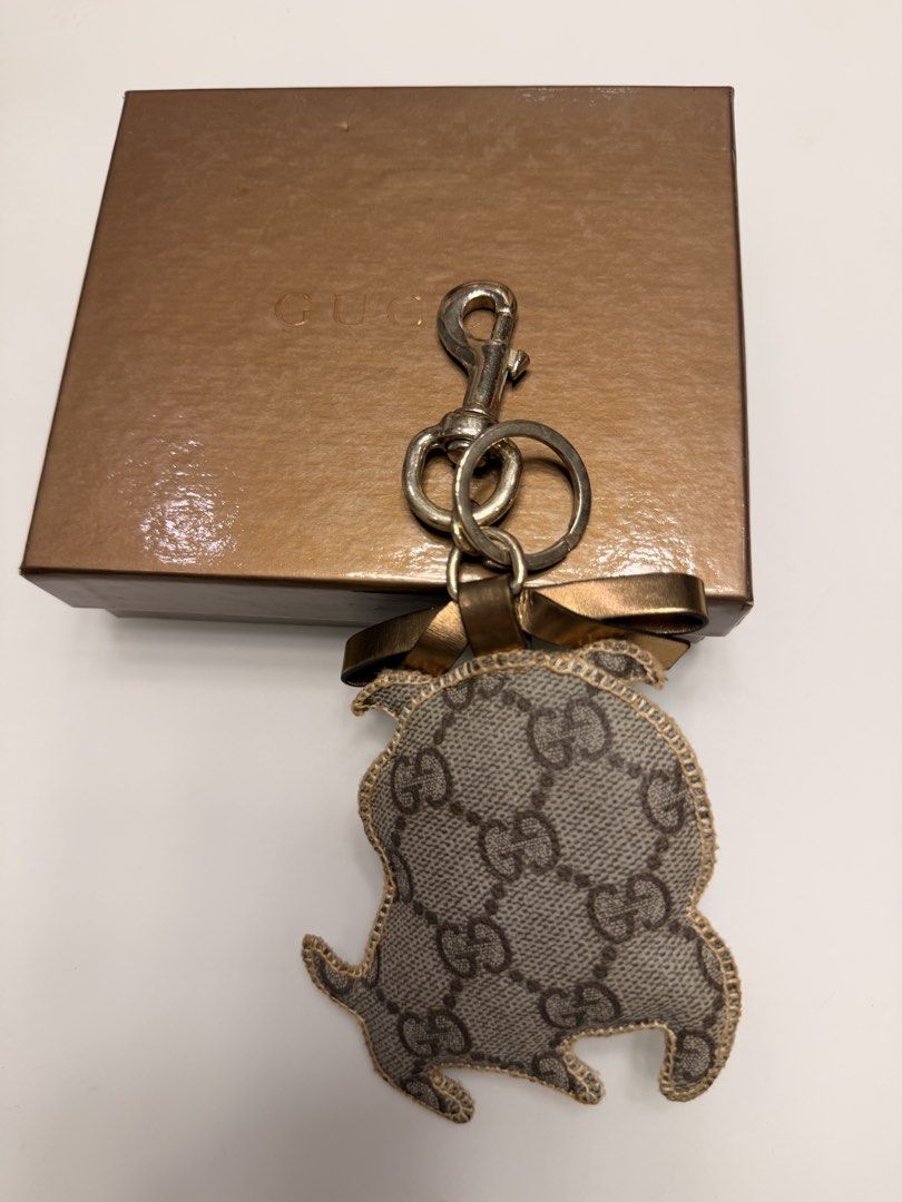 Gucci Dog Keychain Charm with Box (Category: Charms) located in Manila. Submitted by shopbureau (Listing ID 1468096163, Image 2). Description: - Authentic Gucci dog keychain charm with iconic GG monogram canvas - Features premium gold-tone hardware, a secure lobster clasp, and a sturdy key ring - Adorned with a charming little bow detail on top - Comes complete with a branded gold gift box, perfect for gifting - Stylish and fun accessory to eleva