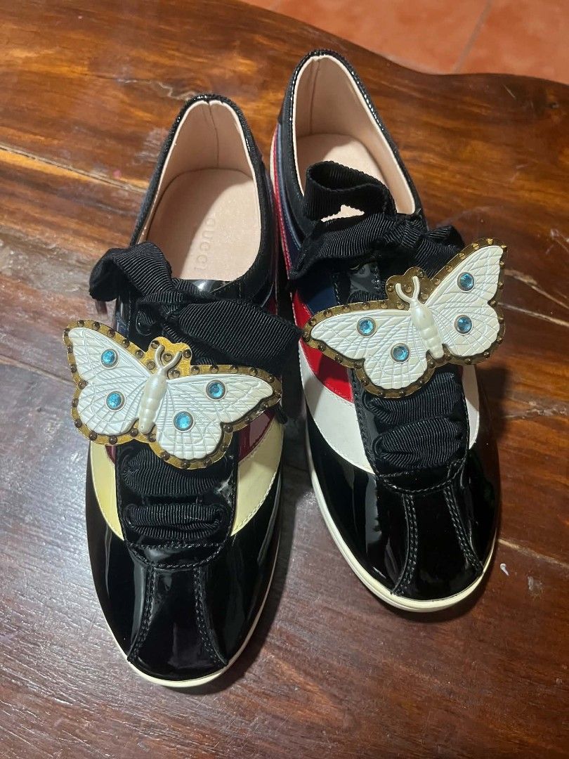 Gucci Falacer Butterfly Sneaker (Category: Sneakers & Footwear) located in Dasmarinas. Submitted by pitato.corner_2621 (Listing ID 1465921776, Image 2). Description: It is crafted from sleek black patent leather and accented with the brand's iconic retro-inspired color blocking on the side panels. Its standout feature is the detachable pearl and crystal butterfly charm clipped across the wide ribbon laces..