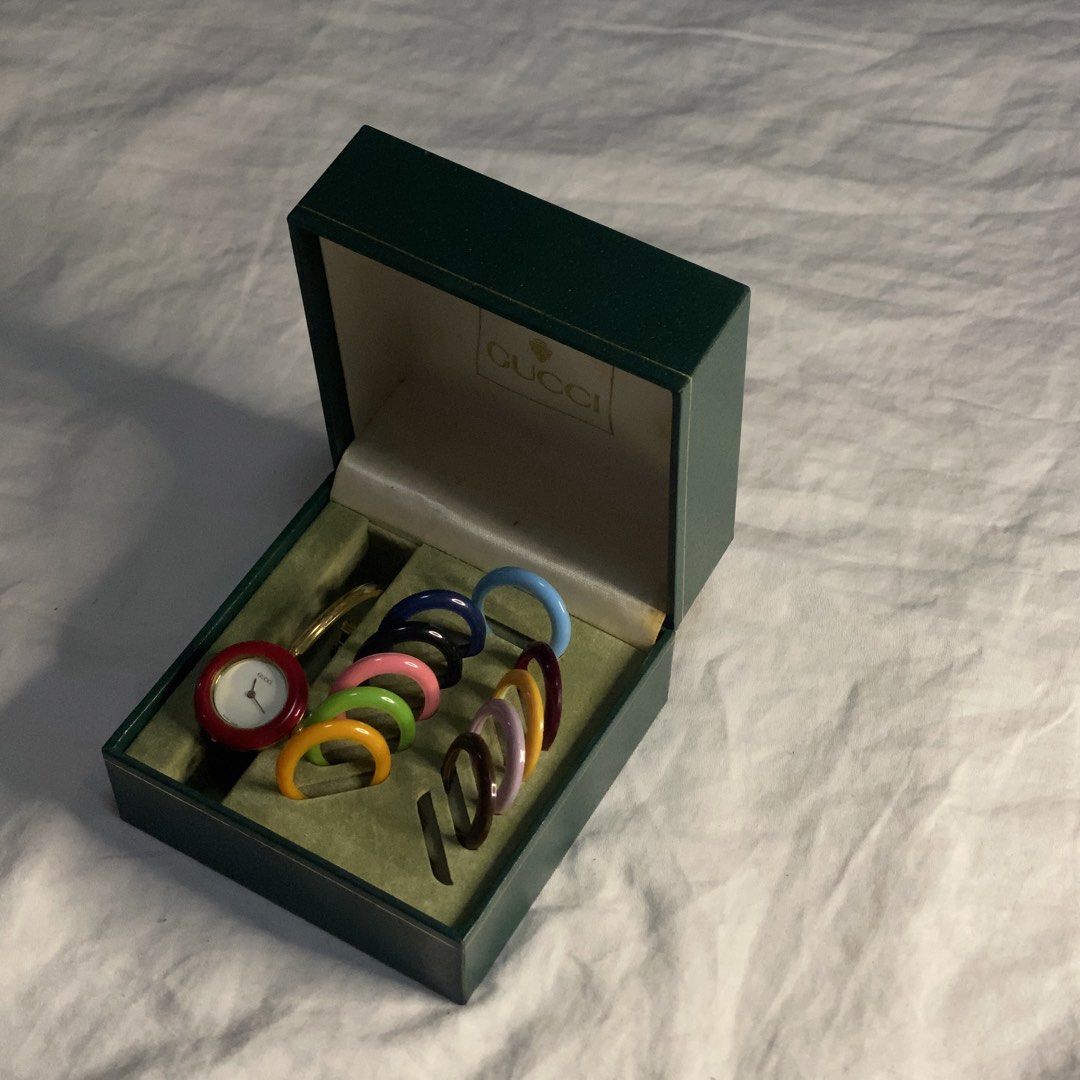 Gucci Interchangeable Bezel Bangle Watch Set (Category: Women's Watches) located in Quezon City. Submitted by suzue.xen (Listing ID 1468099747, Image 2). Description: - Vintage Gucci gold-tone bangle watch - Comes with 8 interchangeable colorful bezels (red currently attached; yellow, green, pink, black, blue, purple, and brown spares included) - Includes original green Gucci logo storage box - Classic collector's item - Perfect for versatile sty