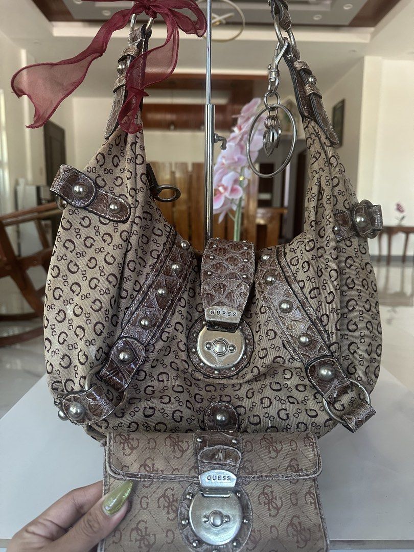 Guess Monogram Shoulder Bag with Matching Wallet (Category: Shoulder Bags) located in Manila. Submitted by goldenhorse-dafc (Listing ID 1468095809, Image 3). Description: Guess shoulder bag covered in the signature brown monogram print. Faux croc-embossed leather trim with silver-toned hardware and stud details. Includes a matching long wallet with a turn-lock closure. Cute maroon ribbon attached to the strap. Silver key ring charm hanging from t