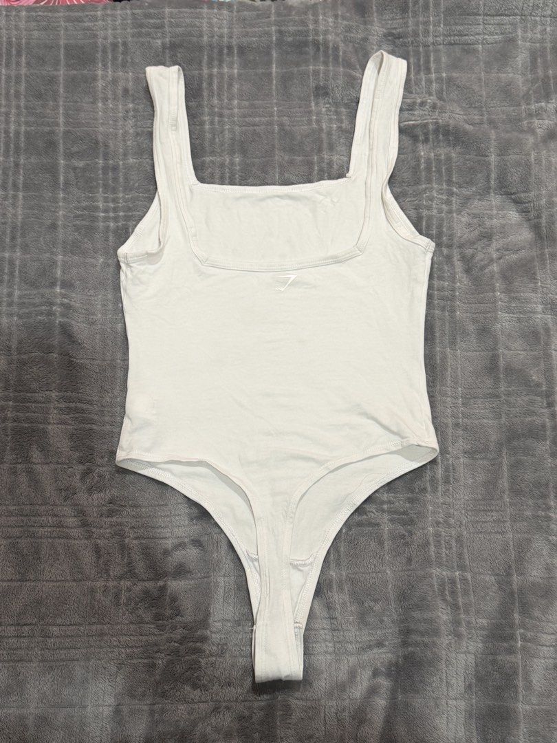 Gymshark White Square Neck Thong Bodysuit Size S (Category: Sleeveless) located in Bulacan. Submitted by richelleregala (Listing ID 1468078685, Image 2). Description: - Brand: Gymshark - Style: Square neck bodysuit - Color: White - Size: S - Material: 95% cotton, 5% elastane (soft stretch fabric) - Details: Thong cut, snap button closure, small silver heat-sealed logo near neckline.
