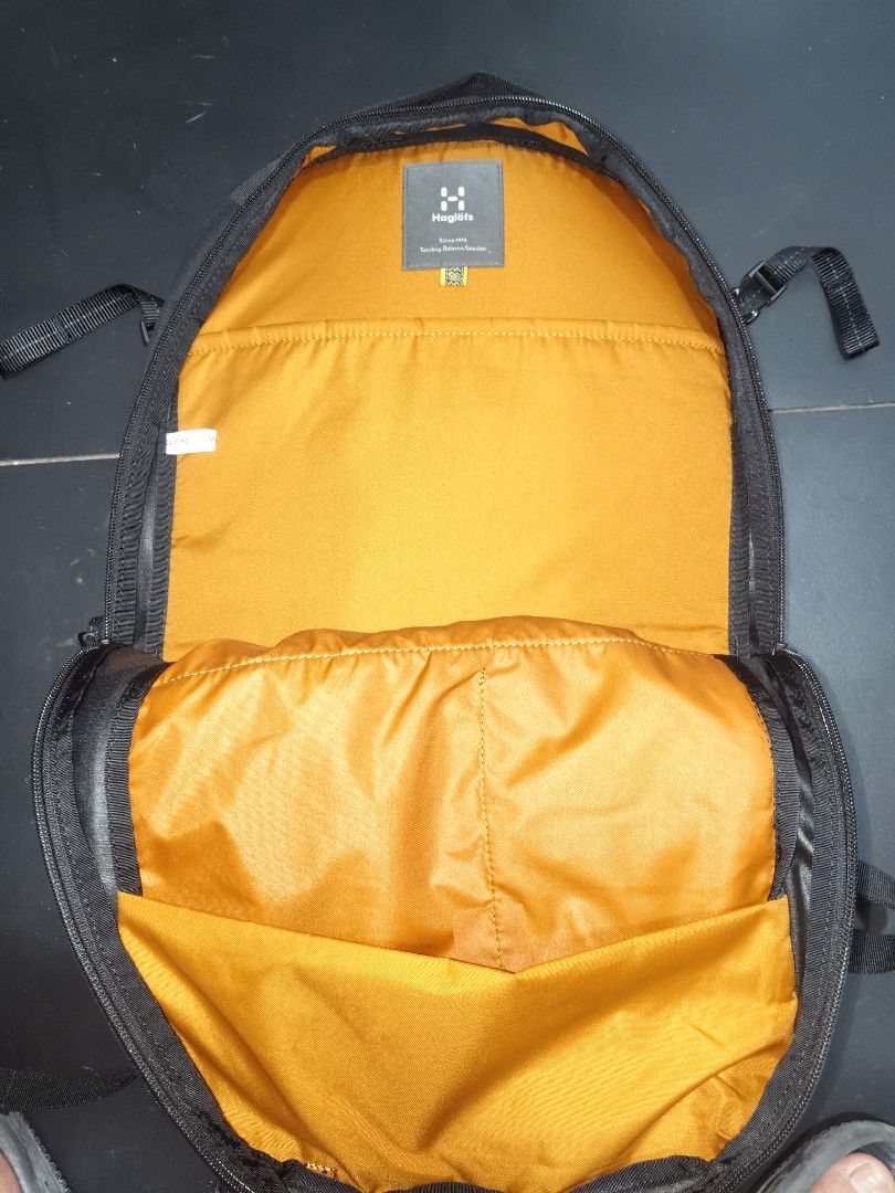 Haglöfs Black Backpack with Orange Interior (Category: Backpacks) located in San Juan City. Submitted by swiftfox.62e2f4 (Listing ID 1468138240, Image 2). Description: - Brand: Haglöfs - Color: Black with bright yellow-orange inner lining - Condition: Clean exterior, sturdy build - Comfort & Support: Mesh back panel, padded shoulder straps, and adjustable sternum strap with buckle - Storage & Pockets: Spacious main compartment, heavy-duty front z
