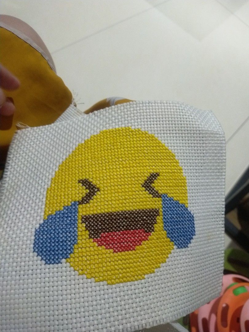 Handmade Cross Stitch Laughing Crying Emoji (Category: Handmade Craft) located in Pagadian. Submitted by kimygo (Listing ID 1468158310, Image 1). Description: - Handmade cross stitch featuring the iconic laughing-crying emoji - Bright yellow face with blue tears and wide open mouth - Stitched neatly on sturdy white plastic mesh canvas - Great for wall hanging or desk display - Fun craft piece with unfinished edges.