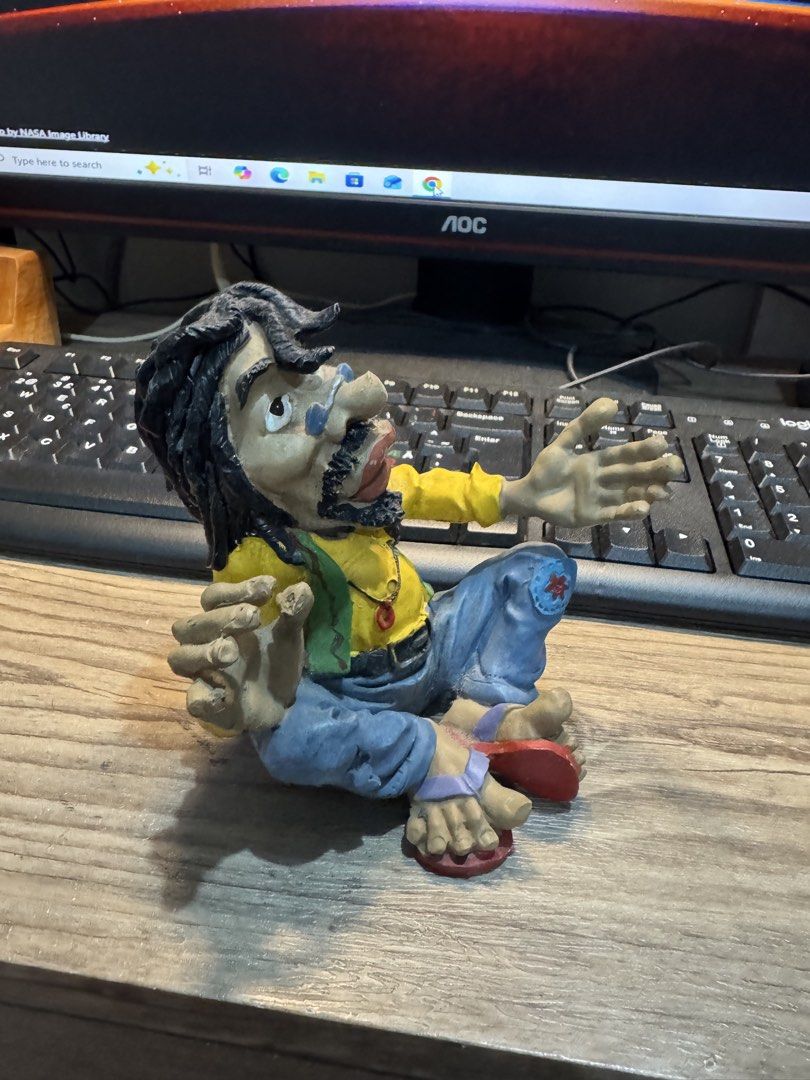 Handmade Hippie Man Figurine with Dreadlocks (Category: Figurines & Statues) located in Cavite. Submitted by marcuz1316 (Listing ID 1468206902, Image 3). Description: Quirky handmade figurine sitting cross-legged. Long black dreadlocks, yellow long-sleeve shirt, green vest, and blue jeans with a patch on the knee. Wearing red flip-flops and a pendant necklace. Detailed facial features including a mustache and beard. Palm-sized decorative piece. M