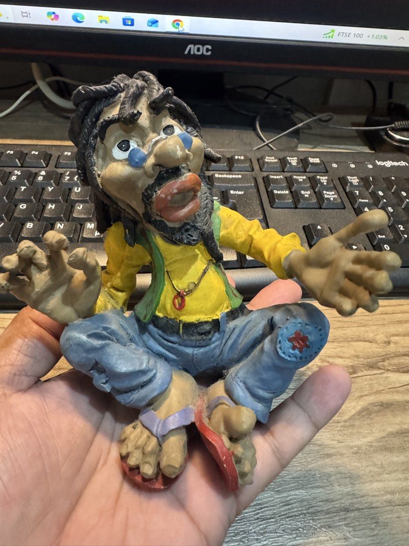 Handmade Hippie Man Figurine with Dreadlocks (Category: Figurines & Statues) located in Cavite. Submitted by marcuz1316 (Listing ID 1468206902, Image 1). Description: Quirky handmade figurine sitting cross-legged. Long black dreadlocks, yellow long-sleeve shirt, green vest, and blue jeans with a patch on the knee. Wearing red flip-flops and a pendant necklace. Detailed facial features including a mustache and beard. Palm-sized decorative piece. M