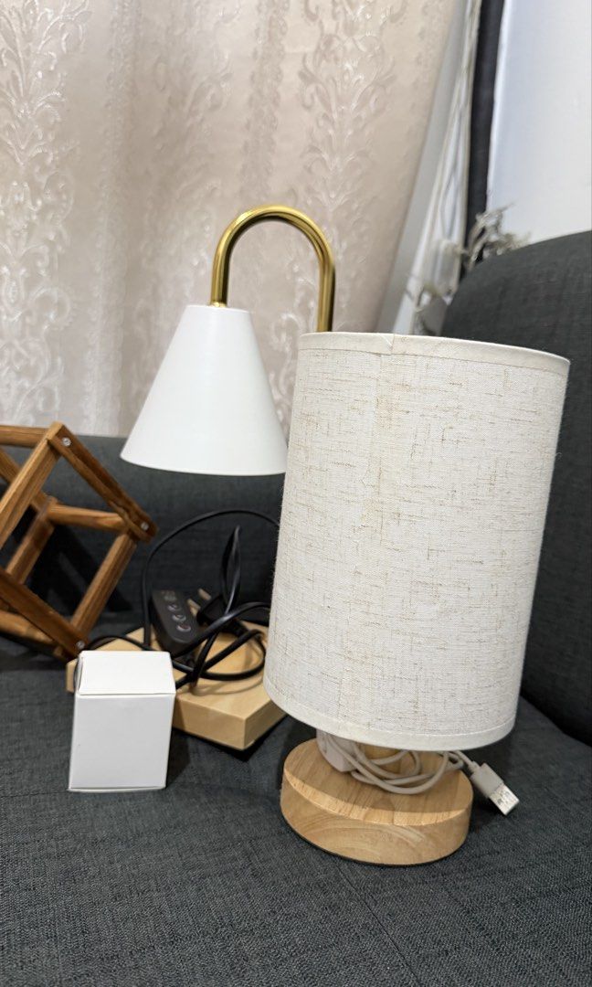 Home Decor Bundle – 2 Lamps + Wooden Wine Rack. (Category: Lighting) located in Manila. Submitted by nessaph (Listing ID 1468173035, Image 2). Description: HOME DECOR BUNDLE FOR SALE 🏡✨ Selling 3 items together: * Gold & White Candle Warmer Lamp – In good condition, well maintained. * Small Bedside Lamp – Used, with visible signs of wear. Features a modern fabric shade, wooden base, and USB-powered connection. * Foldable Wooden Wine Rack – Pract