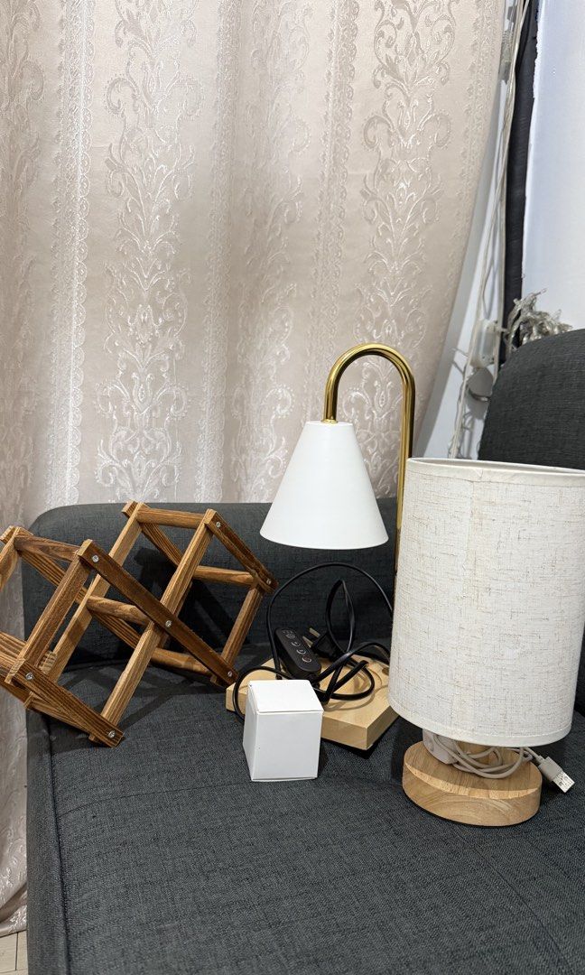 Home Decor Bundle – 2 Lamps + Wooden Wine Rack. (Category: Lighting) located in Manila. Submitted by nessaph (Listing ID 1468173035, Image 1). Description: HOME DECOR BUNDLE FOR SALE 🏡✨ Selling 3 items together: * Gold & White Candle Warmer Lamp – In good condition, well maintained. * Small Bedside Lamp – Used, with visible signs of wear. Features a modern fabric shade, wooden base, and USB-powered connection. * Foldable Wooden Wine Rack – Pract