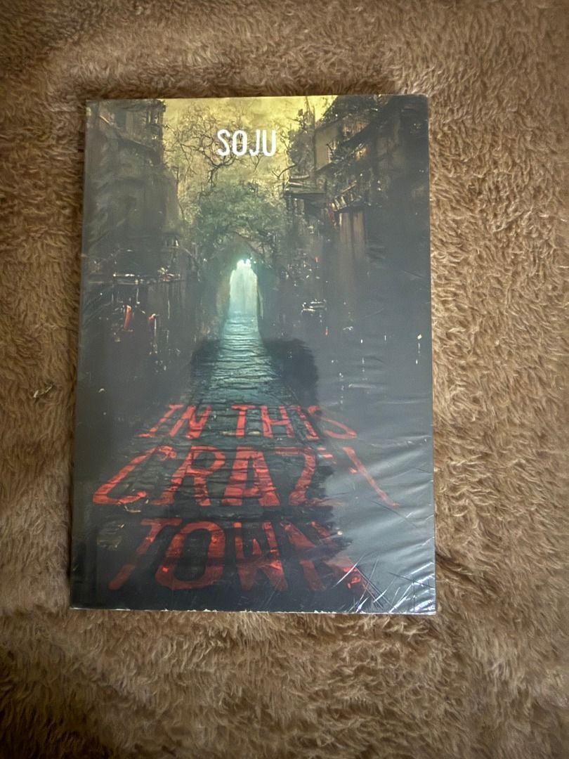 In This Crazy Town by Soju (Category: Storybooks) located in Manila. Submitted by bellevuebooks (Listing ID 1468236547, Image 1). Description: Soju's book titled In This Crazy Town. Dark moody cover art featuring a narrow stone street lit by a distant green glow. Red lettering sprawled across the pavement. Still sealed in the original plastic wrapping. Clean edges, no dents or tears on the cover. Unopened copy..