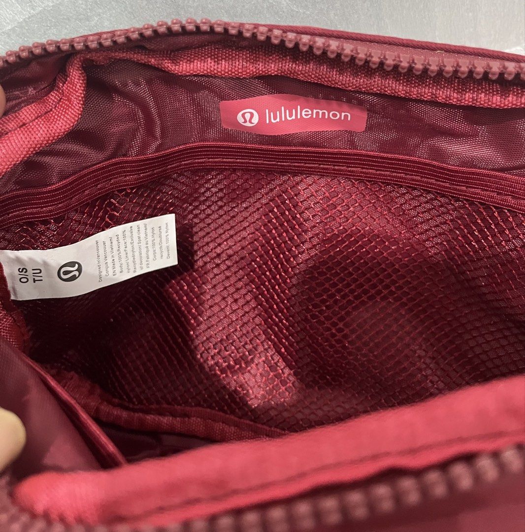 Inspired Lululemon Everywhere Belt Bag with Branded Strap (Category: Cross-body Bags) located in Talisay. Submitted by cherylu (Listing ID 1468267030, Image 3). Description: - Color: Rich burgundy with dark red hardware - Design: Features a trendy striped strap with repeating Lululemon text logo - Branding: Iconic metallic Lululemon logo on the front face - Storage: Secure zippered main compartment with an interior mesh pocket - Details: Clean in