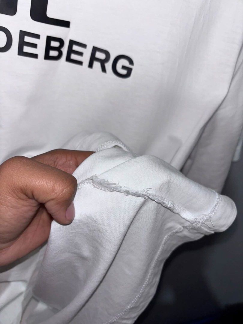 j.lindeberg White T-Shirt Size L (Category: Luxury Apparel) located in Cuyapo. Submitted by mn.finds (Listing ID 1468136745, Image 3). Description: - Brand: J.Lindeberg - Color: White with black chest logo print - Size: Large - Style: short sleeves - Origin: Made in China - Condition: Clean fabric overall, with minor fraying .